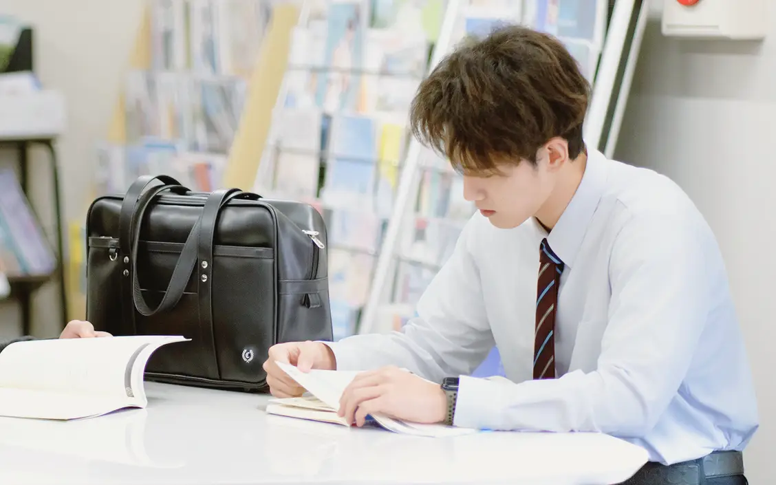 教科書を読み、学ぶ男子生徒